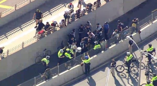 Police officers with protestors on the Brooklyn Bridge.