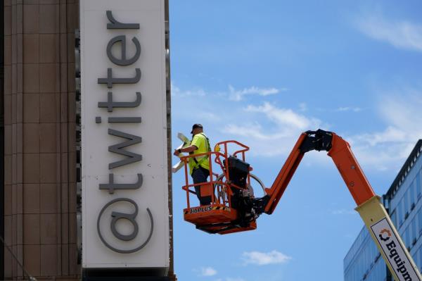 A workman removes a character from a sign on the Twitter headquarters building.
