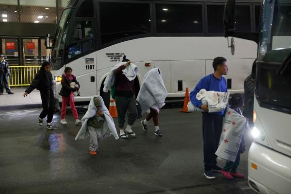 Migrants from Laredo, Texas transferring buses at New York port authority terminal with police handing out tickets, including Bear Pascoe, Lara Rossi, and Marina Bravo present