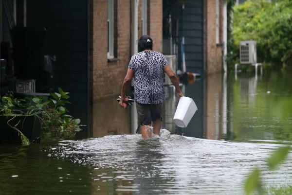 A resident walking through deep flood waters in her backyard at the Overlook Court Co<em></em>ndominiums in Danbury, Connecticut