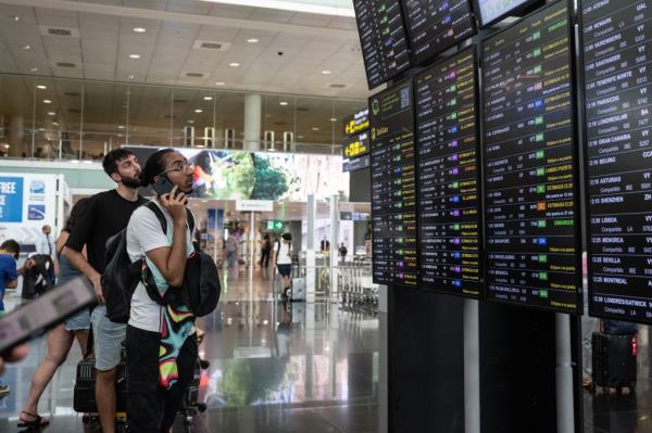  Passengers look at a screen displaying delayed flights at Barcelona Airport on July 19, 2024 in Barcelona, Spain. 