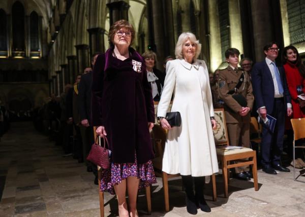 Queen Camilla with another woman in a room full of people at Salisbury Cathedral event.