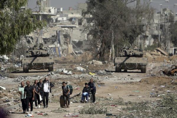 Palestinians on a road with damaged buildings in Gaza.