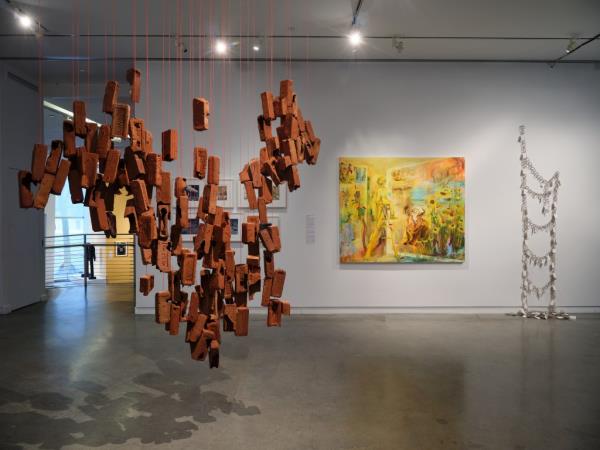 An interior image of the Bronx gallery's AIM Biennial, showcasing a hanging sculpture made of bricks.