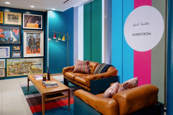 Interior image of Nordstrom's colorful Paul Smith clubhouse, with couches, pink and blue stripes, and a wall full of paintings.