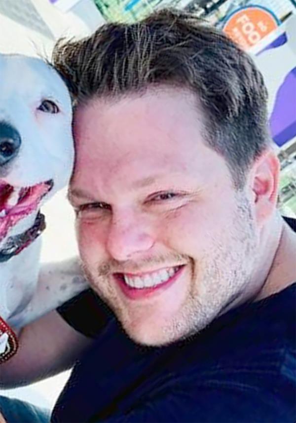 Jordan Willis, Kansas City Chiefs fan and HIV scientist, smiling with a dog.