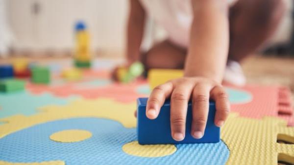 closeup of a toddler holding a block on a play mat