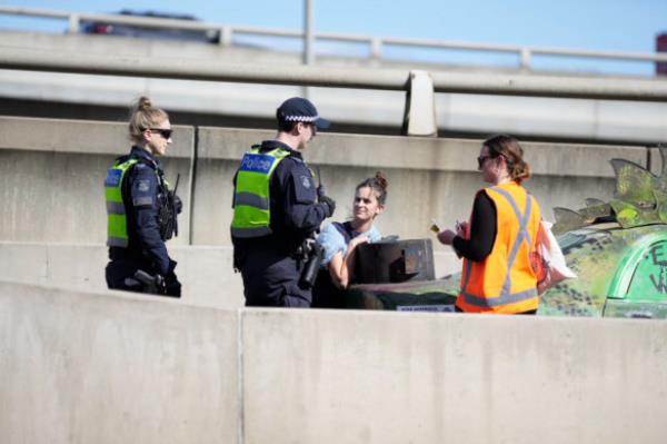 Police are trying to remove the 27-year-old woman disrupting traffic on the West Gate Freeway.