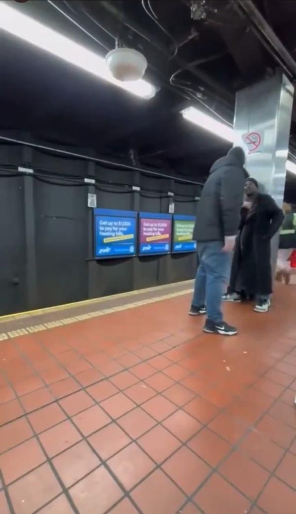 The two man are seen arguing near the subway platforms edge as the train can be heard pulling into the station.
