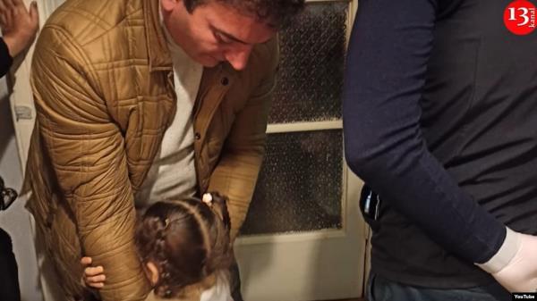 In a screengrab from video, the 3-year-old daughter of Azeri journalist Aziz Orujov hugs her father before he is arrested in November. (Kanal 13 YouTube channel)